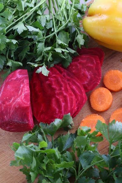 Gepelde rode bieten en verse wortelen voor de salade op een houten tafel — Stockfoto