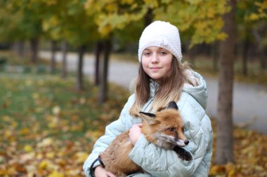 Sonbahar parkında kızıl tilkili bir kız.