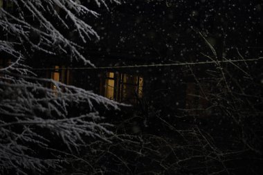 Pencere yağan karın arka planına karşı aydınlandı