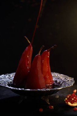 Siyah arka planda kırmızı şarapta haşlanmış armut.