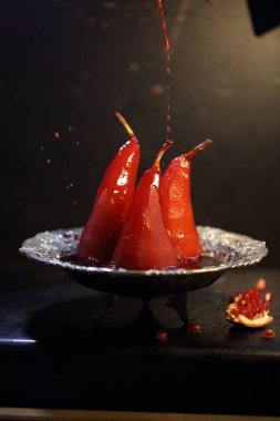 Siyah arka planda kırmızı şarapta haşlanmış armut.