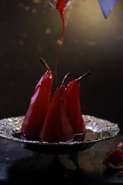 Siyah arka planda kırmızı şarapta haşlanmış armut.