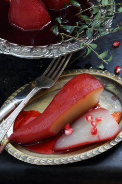 Siyah arka planda kırmızı şarapta haşlanmış armut.