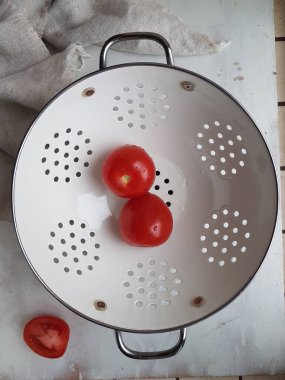 Beyaz arka planda beyaz kevgir soslu kırmızı domates.