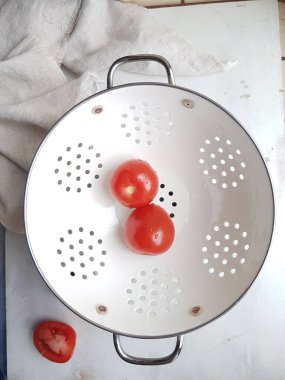 Beyaz arka planda beyaz kevgir soslu kırmızı domates.