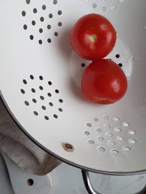 Beyaz arka planda beyaz kevgir soslu kırmızı domates.