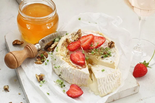 Camembert with strawberries and wine on a white background