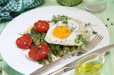 Yeşil fasulyeli omlet, yeşil ahşap arka planda beyaz şaraplı domates.