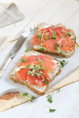 Beyaz tabakta somon ve krem peynirli sandviç.