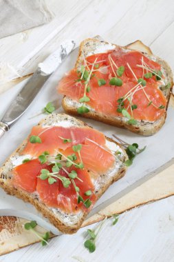 Beyaz tabakta somon ve krem peynirli sandviç.