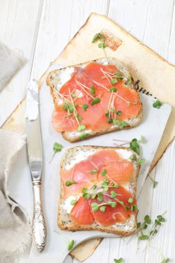 Beyaz tabakta somon ve krem peynirli sandviç.