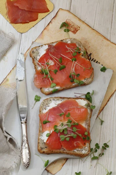 Beyaz tabakta somon ve krem peynirli sandviç.