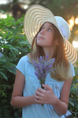 Bir buket lavantalı şapkalı kız.