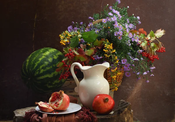 Water-melon, a pomegranate, a white jug and a bouquet in a wattl — Stock Photo, Image