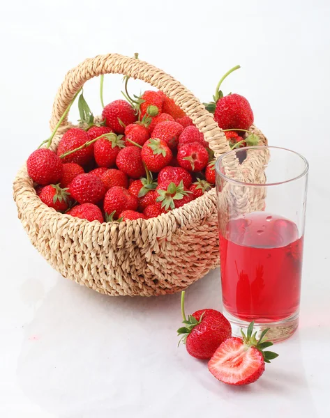 Frische reife Erdbeere in einem aufgewetzten Korb und einem Glas Erdbeere — Stockfoto