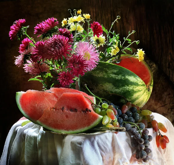 Nature morte avec un melon d'eau et des raisins et un bouquet d'asters — Photo