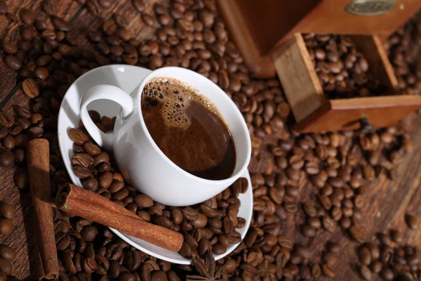 Coffee in a white cup in an environment of coffee grains, cinnam — Stock Photo, Image