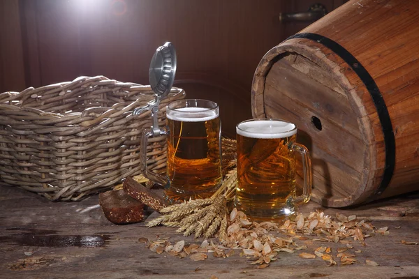 Beer with foam in a transparent mug, a wooden butt, rye bread an — Stock Photo, Image