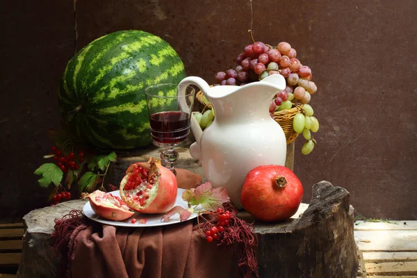 Натюрморт с красным вином, гранатом, виноградом и арбузом — стоковое фото