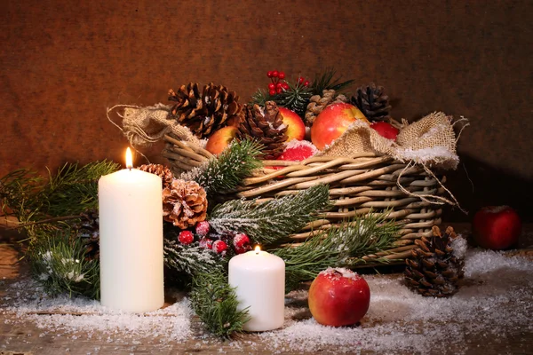 Apples and cones in a wattled basket, candles and a pine branch — Stock Photo, Image