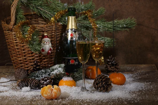 Champanhe, tangerinas e galho de árvore de pele com cones sob neve — Fotografia de Stock