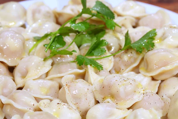 Pelmeni con mantequilla y pimienta molida, con rama de perejil —  Fotos de Stock