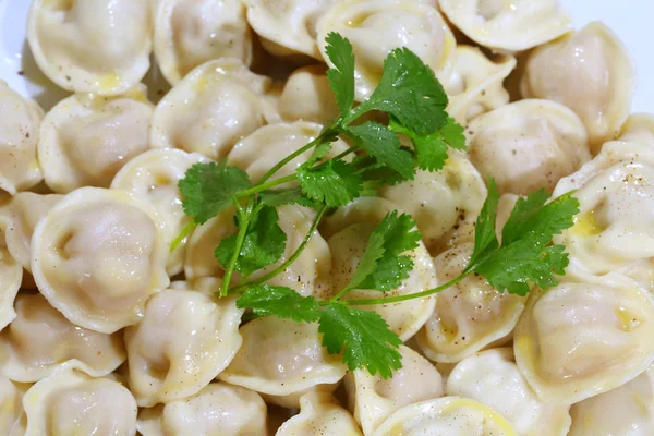 Pelmeni mit Butter und gemahlenem Pfeffer, mit Petersilienzweig — Stockfoto