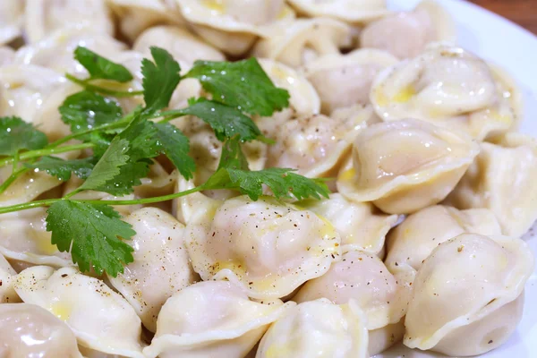 Pelmeni med smör och peppar, med en persilja gren — Stockfoto