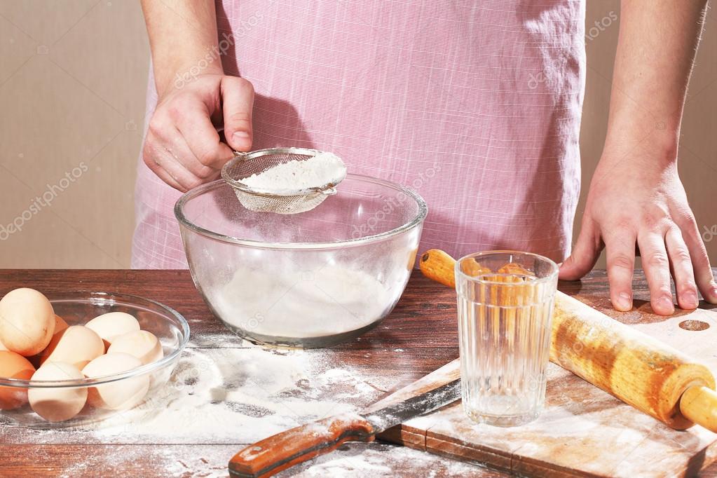 Preparation of pelmeni, man's hand holds a strainer with a flour