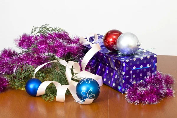 Tinsel, esferas de um ornamento de uma árvore da pele e um pacote de presente — Fotografia de Stock