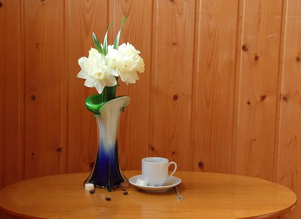 Cup of coffee and bouquet of narcissuses — Stock Photo, Image