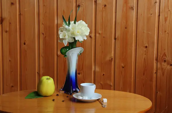 Tasse Kaffee, Bouquet von Narzissen und Apfel — Stockfoto