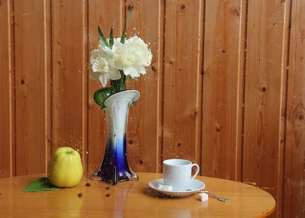 Xícara de café e buquê de narcisos atrás de vidro com chuva — Fotografia de Stock