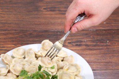 Üzerine tutturulmuş bir fiş elini tutan mantı