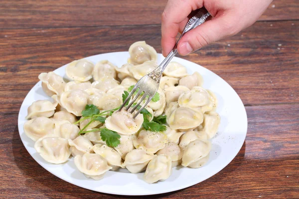 The man's hand holds a plug with pinned on it pelmeni — Stock Photo, Image