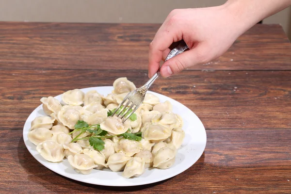 De man's hand houdt een stekker met gevestigd op het pelmeni — Stockfoto