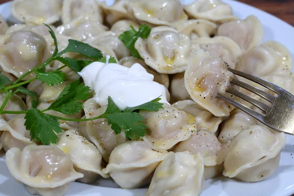 Ekşi krema, tereyağı, maydanoz ve zemin bir dalı ile mantı