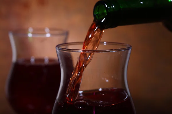 Red wine flows from a bottle in a transparent glass — Stock Photo, Image