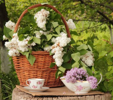 Fincan çay ve leylak ahşap bir saplama üzerinde gerdanlı sepet içinde