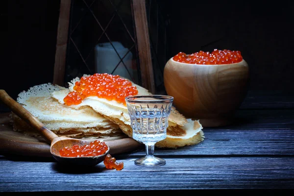 Pannenkoeken met rode kaviaar en een wijn-glas wodka en een oude la — Stockfoto