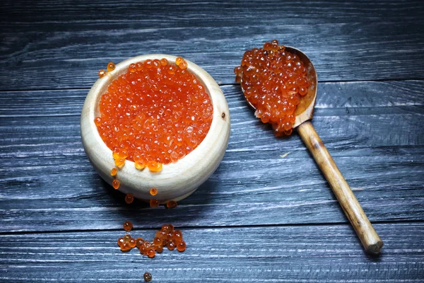 Red caviar in a wooden bowl and a wooden spoon — Stock Photo, Image