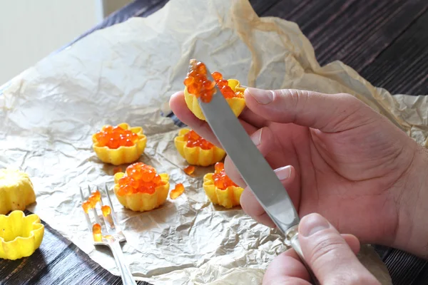 Man's hands impose red caviar in a tartlet — Stock Photo, Image