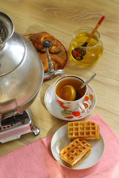 Té de un samovar, con limón, miel, panecillos y pasteles —  Fotos de Stock