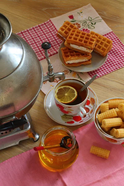 Té de un samovar, con limón, miel, pasteles y obleas —  Fotos de Stock