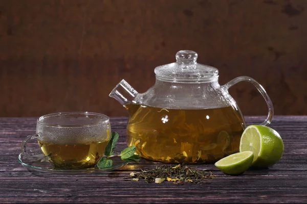 Thee in een glas theepot en een transparante cup met kalk en mint o — Stockfoto