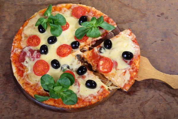 Pièce de pizza sur une pelle en bois — Photo