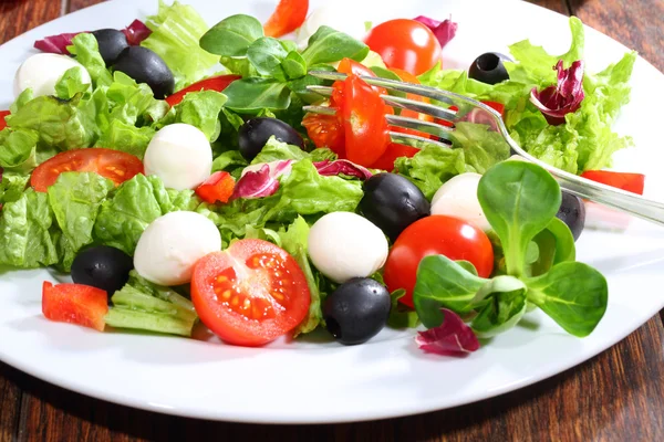 Tomate fixado em uma tomada em salada vegetal — Fotografia de Stock