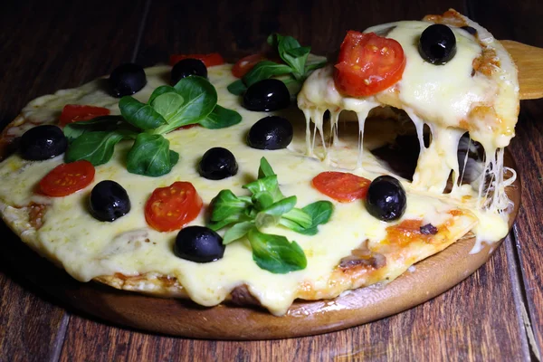 Stuk van een pizza met de gesmolten kaas op een houten schop — Stockfoto