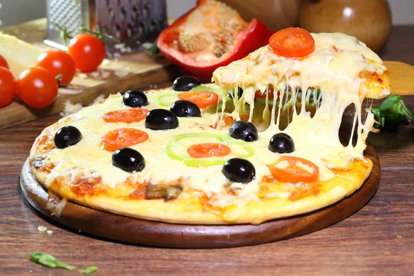 Bucată de pizza cu brânză fuzionată și o roșie pe lemn — Fotografie, imagine de stoc
