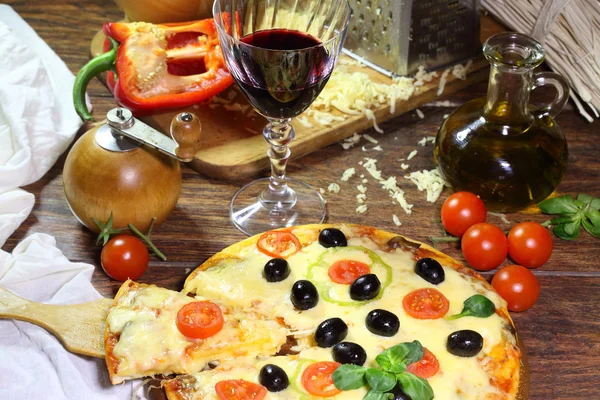 Červené víno v průhledného skla a pizza kus na dřevěné sh — Stock fotografie
